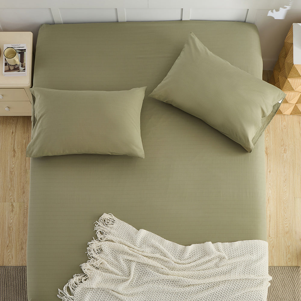Top view of olive green organic grounding sheet with pillows and cream blanket – Terra Solum