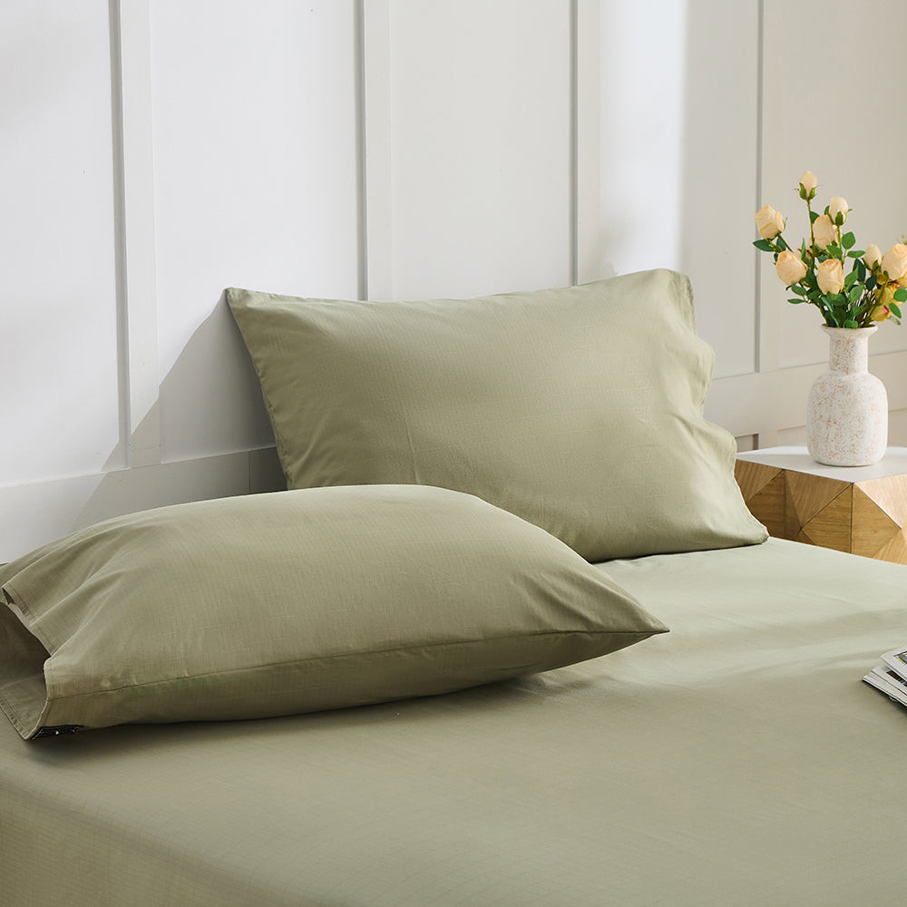 Close-up of olive green organic cotton pillowcase texture and stitching – grounding silver fiber blend
