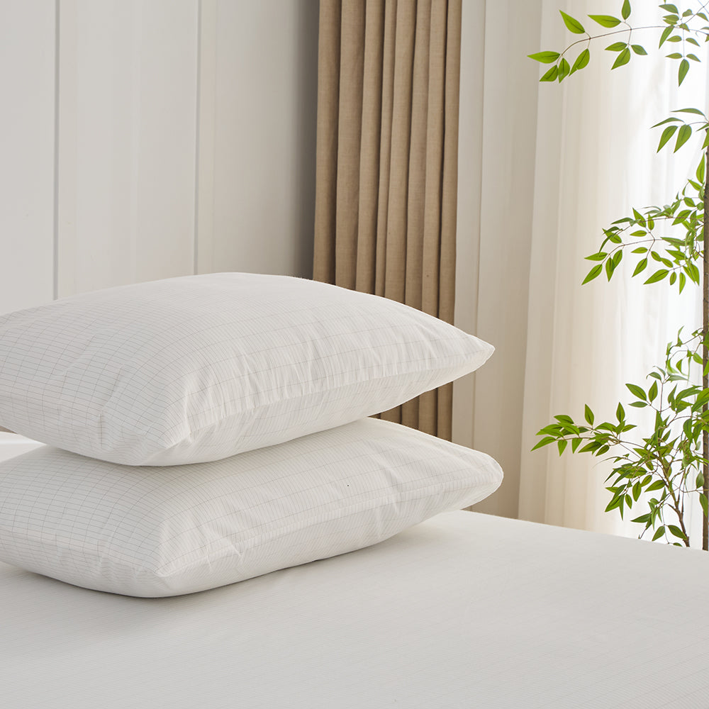 Pure white organic grounding pillowcases set stacked on bed – Terra Solum luxury earthing bedding